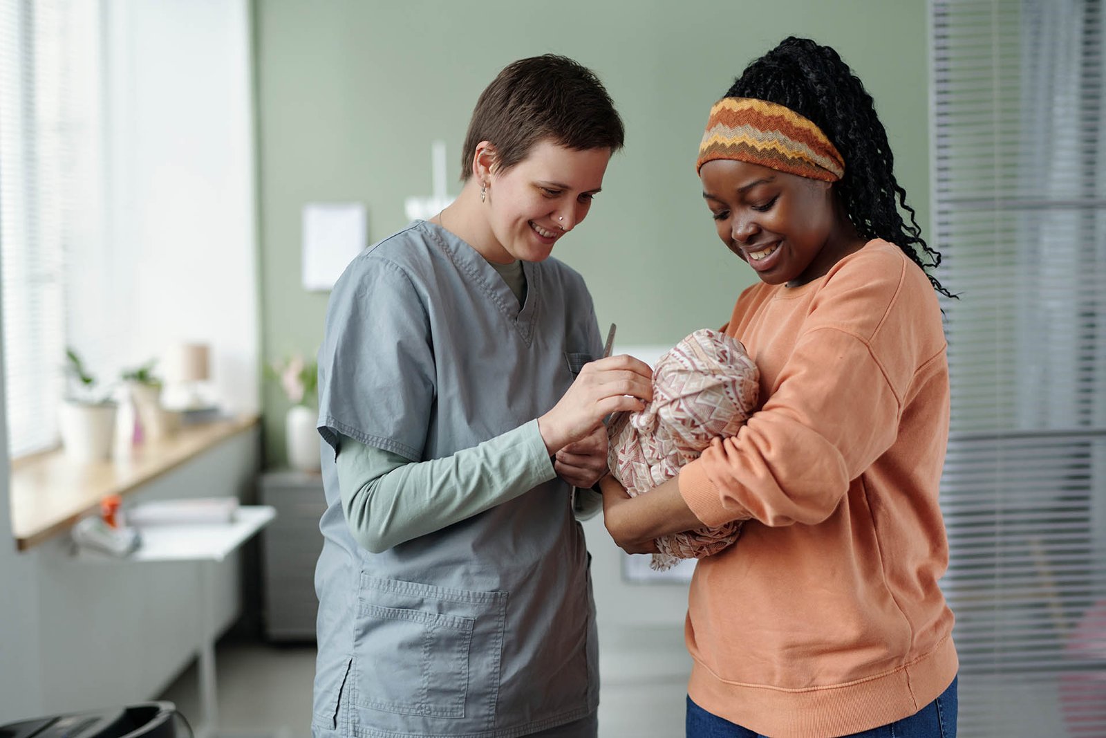 Nurse Interacting with New Mother and Baby in Hospital Room